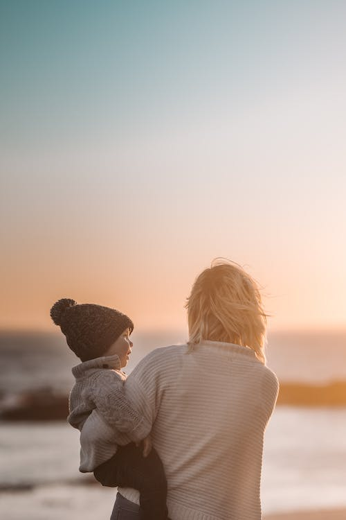 a mother holding her child as they enjoy the sunset