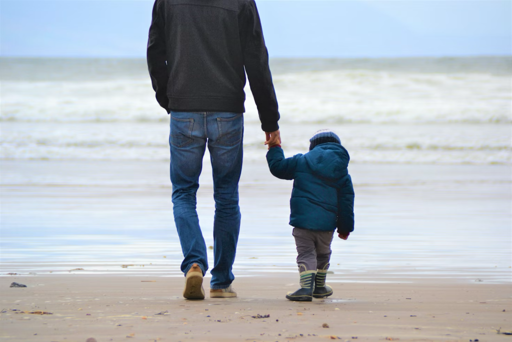 a father holding his son's hand at the beach