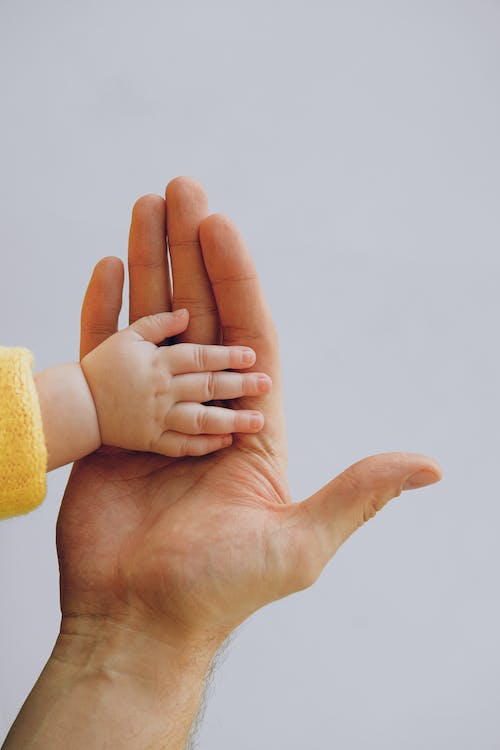 A baby’s hand on their father’s palm