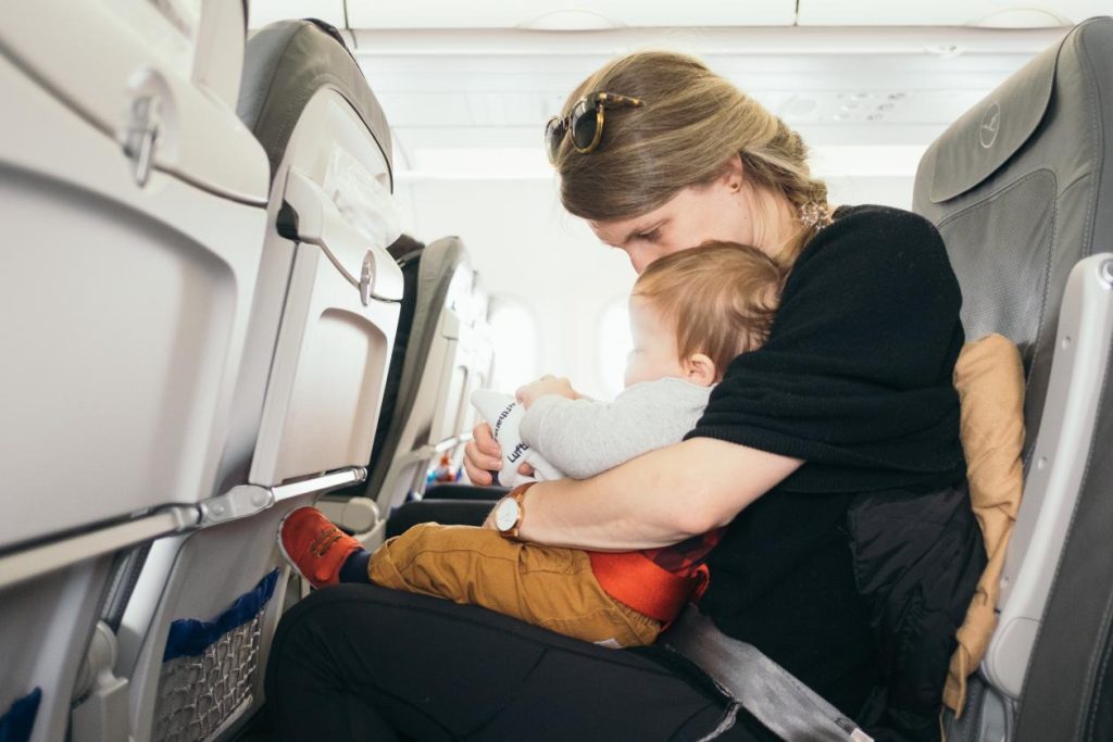 A woman with a child on her lap on a plane