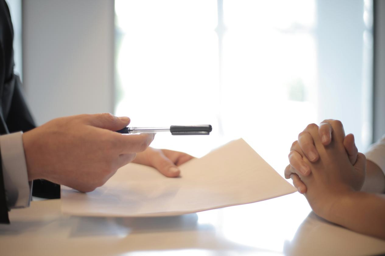 A man giving a pen and a piece of paper to a woman