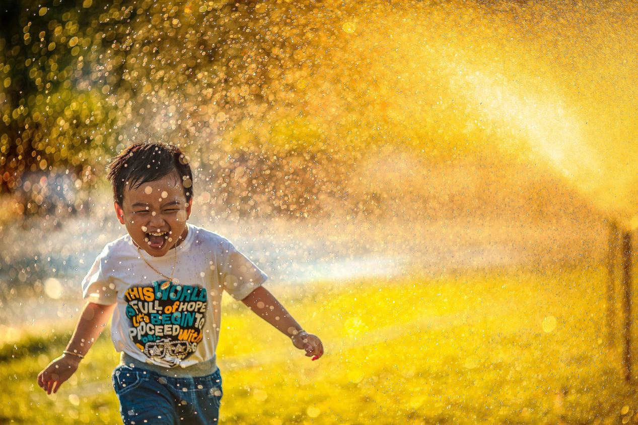 A kid running in a park with confetti all around him