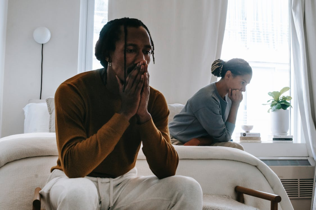 Distressed couple on separate sides of the bed contemplating the emotional aspects of divorce.