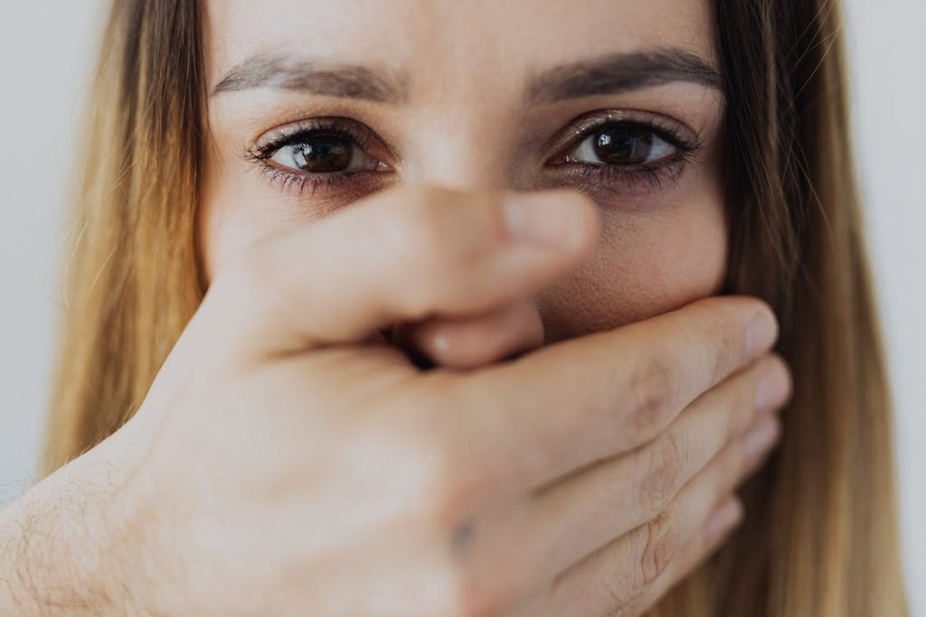 Close-up of a distressed woman’s face being covered by a male.