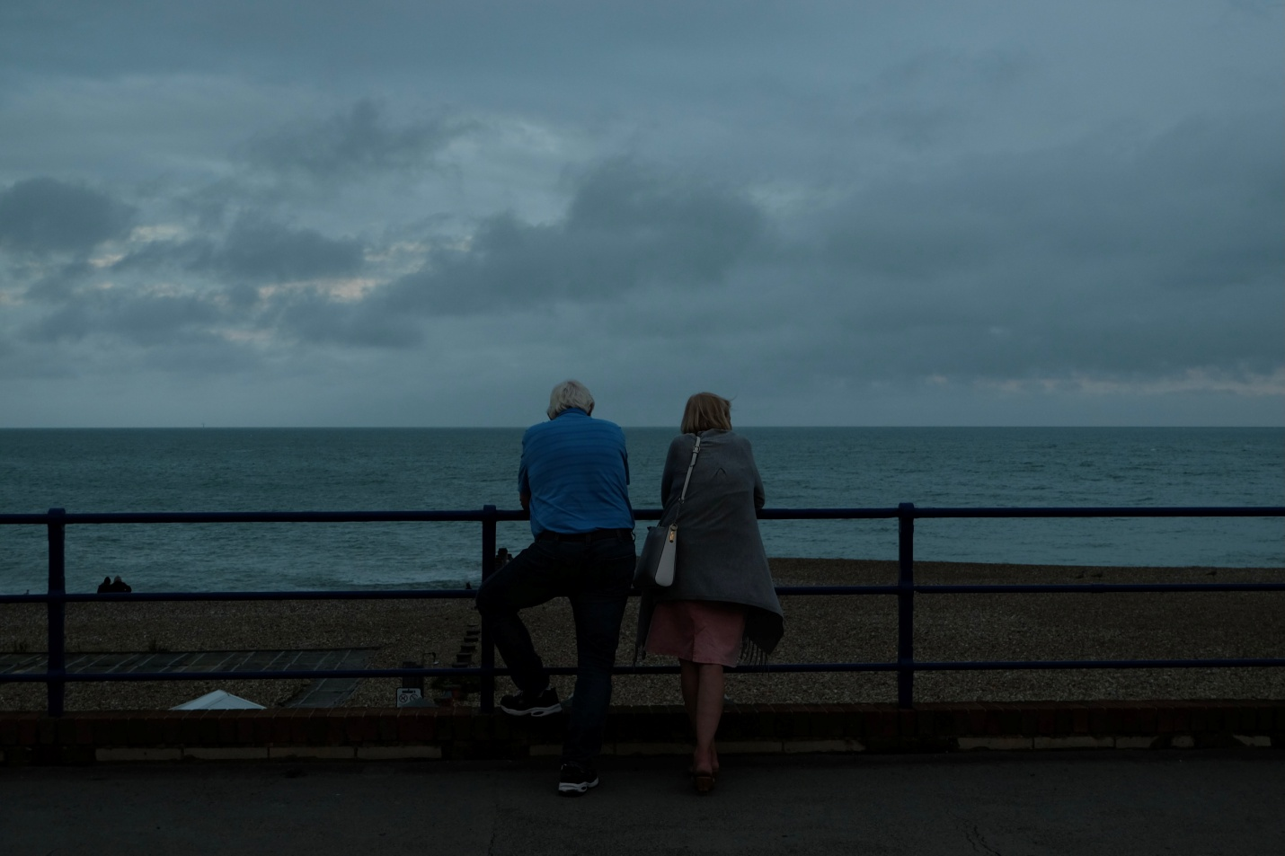 An elderly couple standing on a seashore