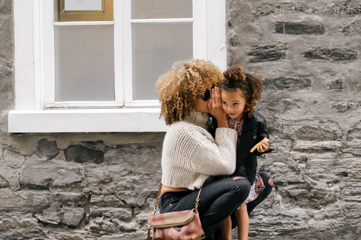 A mother whispering into her child's ear