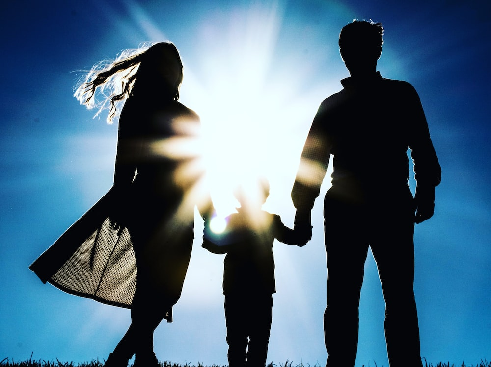 A couple holding their child's hands.