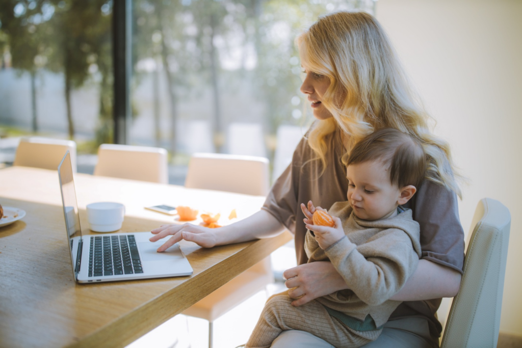 A woman working on a laptop with her son on her lap