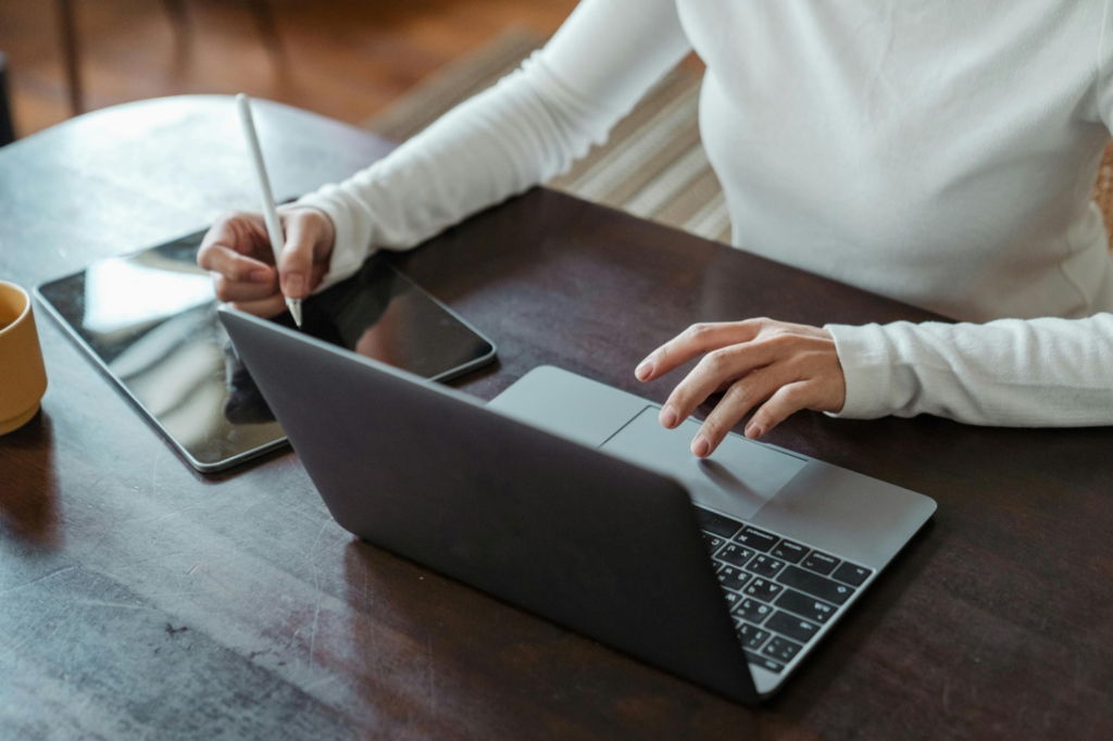 A person using a tablet and laptop simultaneously