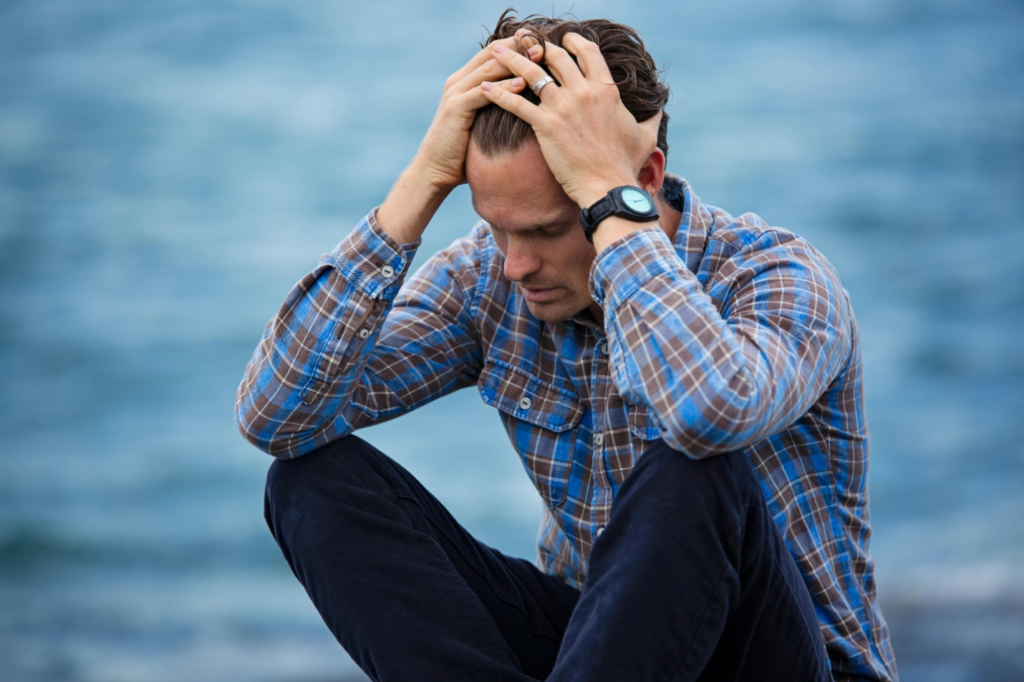 A sad-looking person sitting with his head in his hands