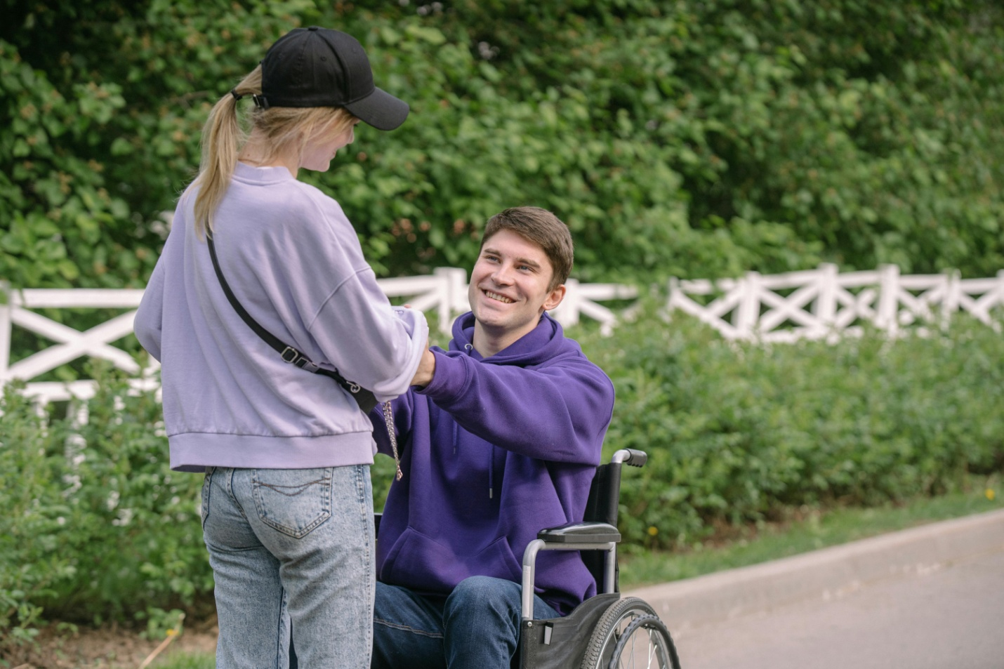 A man in a wheelchair holding a woman's hands