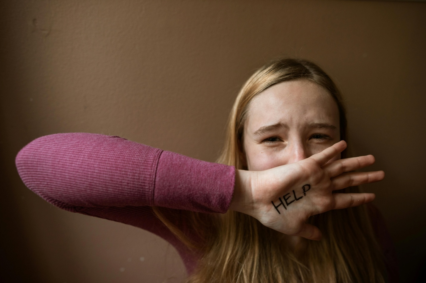 The word 'help' written on a distressed woman's hand