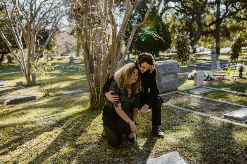 A woman crying in a graveyard while a man tries to comfort her