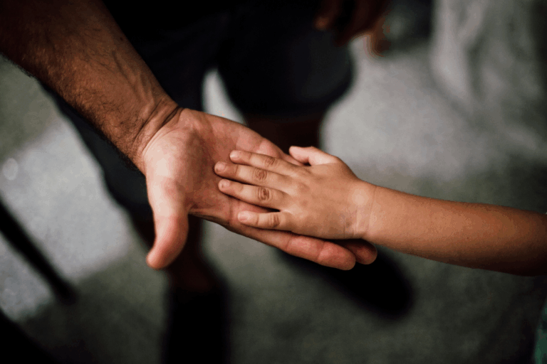 A child placing his hand on his father's hand