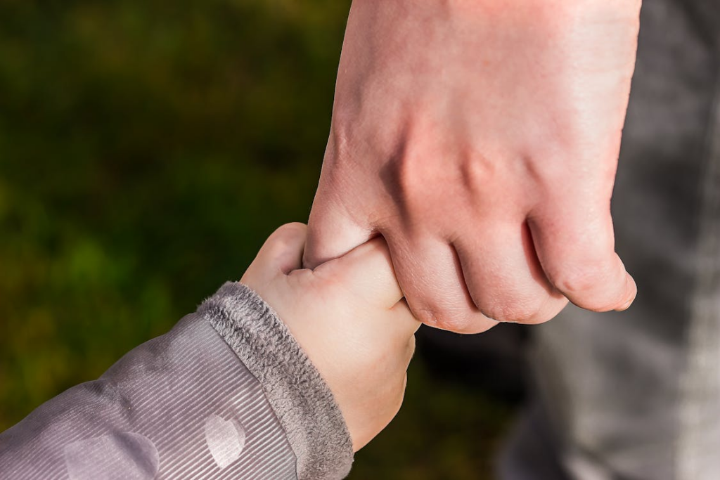 A parent holding their child’s hand