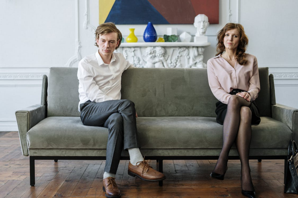 An image of a couple sitting cross-legged on a gray couch