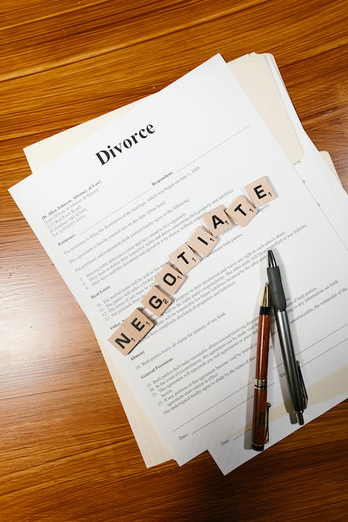 An image of two pens and a divorce agreement placed on a brown table