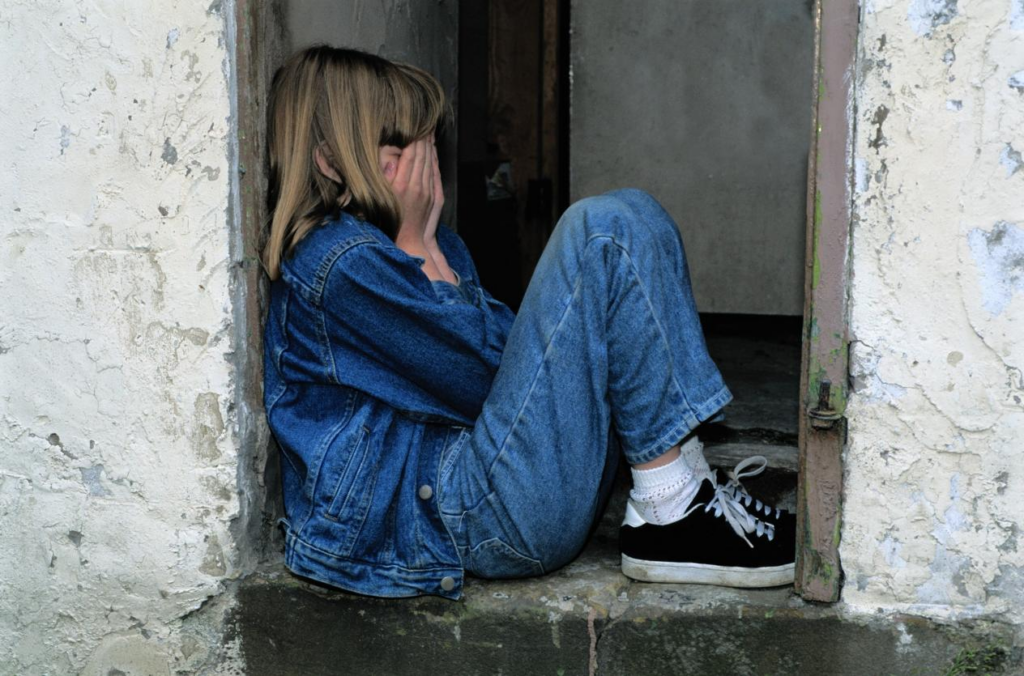 A kid sitting with their eyes covered
