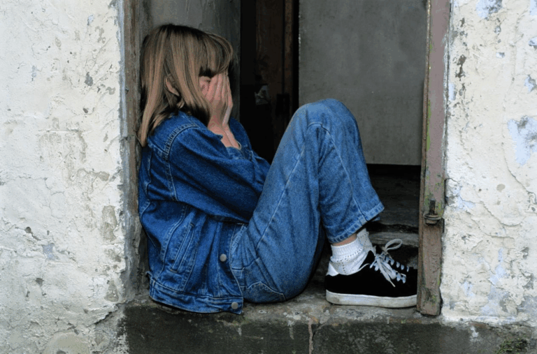 A kid sitting with their eyes covered