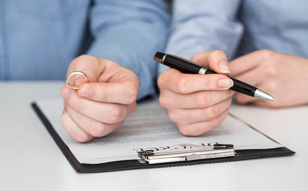 Woman signing a divorce contract while a man holds a ring, indicating legal separation from a common law marriage.