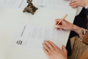 A couple signing divorce papers in a divorce attorney’s office, discussing property division.