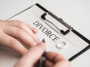 A man preparing to sign divorce papers, with a wedding ring lying on the documents.