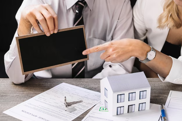 A miniature house and documents on a table