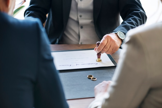 A legal person stamping a divorce certificate with marriage rings on the table.