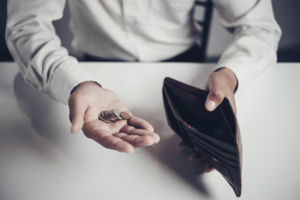 Man holding an empty wallet and a few coins in his palm, symbolizing financial struggle to pay child support