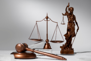 A wooden gavel, Lady of Justice statue, and Justice Scale on a white surf