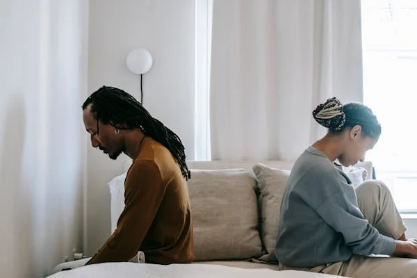 A Couple sitting on opposite sides of the bed showing emotional strain before a divorce