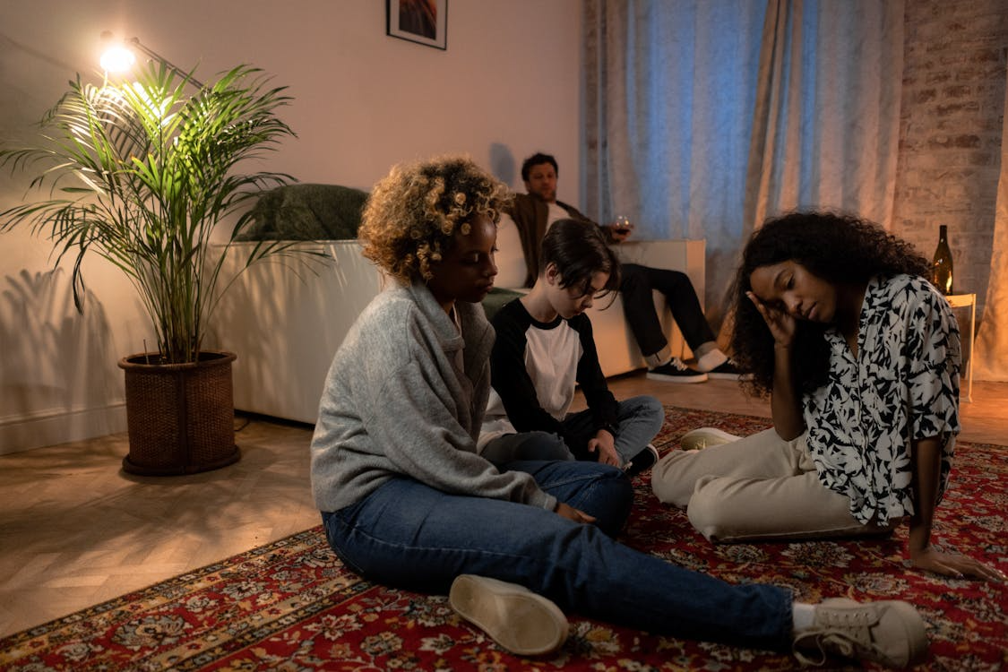 a family sitting on the sofa and floor due to family issues and arguments