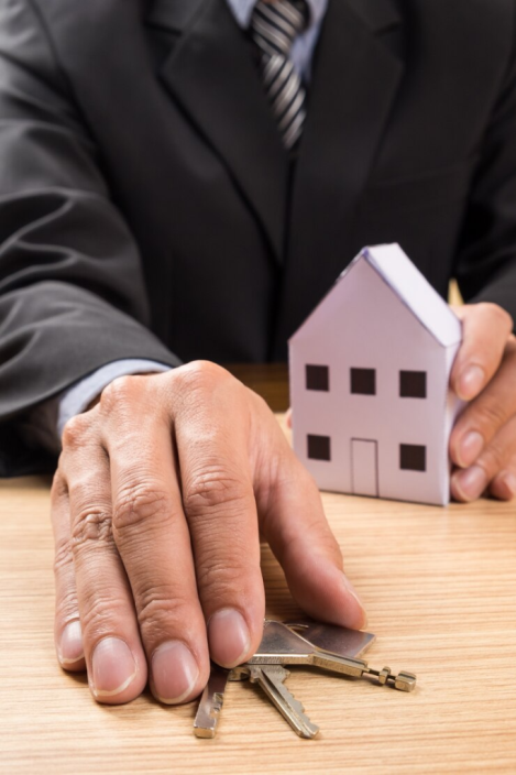 A person holding keys and a miniature house