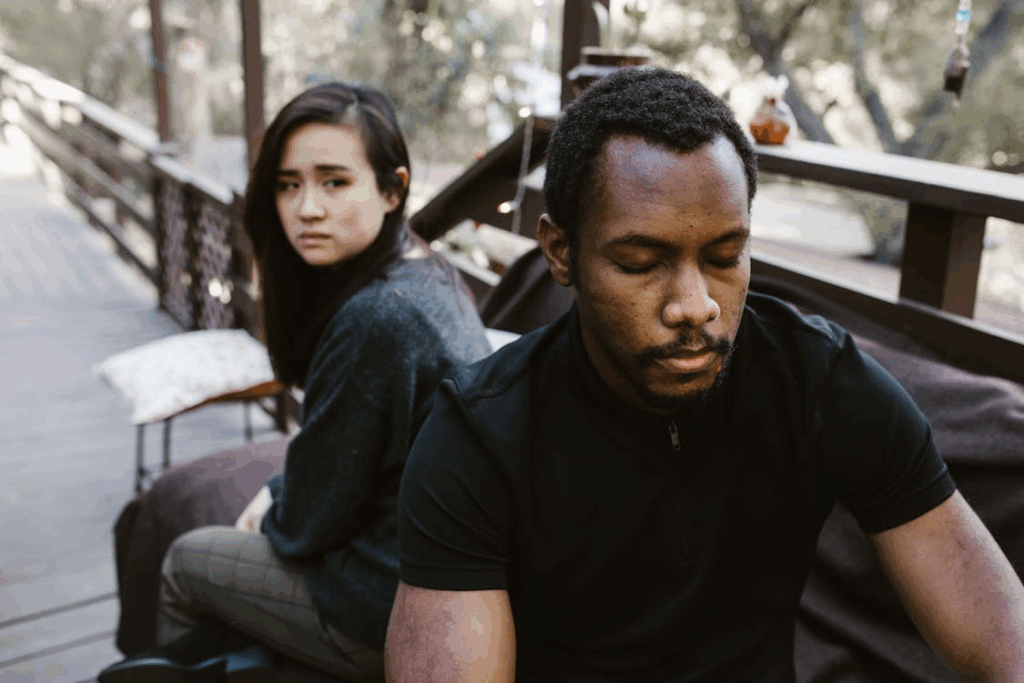 A couple sitting apart on a couch, both frustrated and emotionally distant during a divorce.