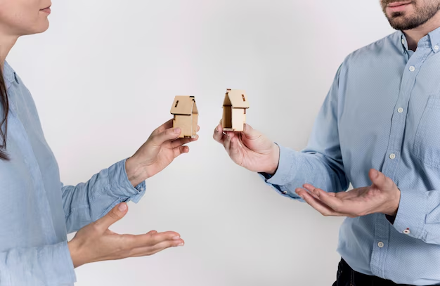 Two people holding miniature houses