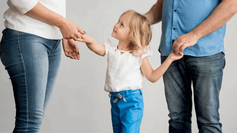 Child standing between two parents managing co-parenting responsibilities
