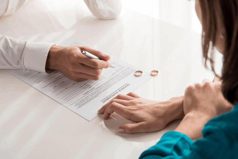 a couple signing a divorce paper with their rings on the table