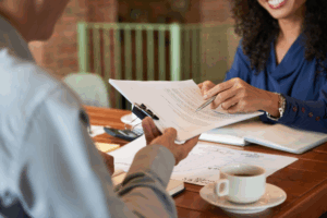 a man at a lawyer's desk being handed paper for signing