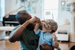 a military man playing with his child with his military cap