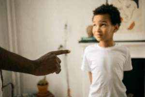  a small, scared boy being scolded by a man pointing his finger at him