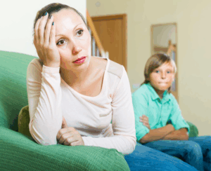 a boy looking at his stressed mother on a sofa