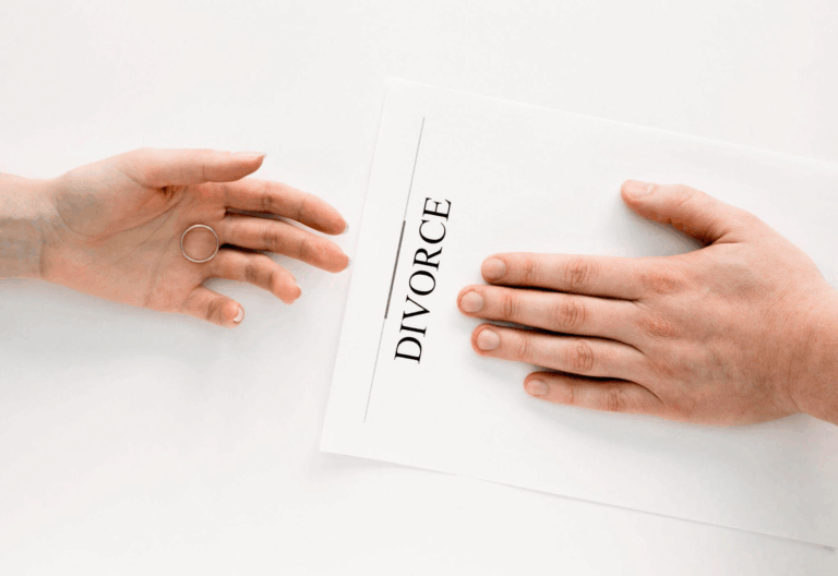 A hand pushing a divorce agreement across a white surface.
