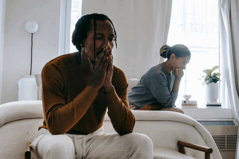 a couple upset with each other, sitting on the bed after an argument
