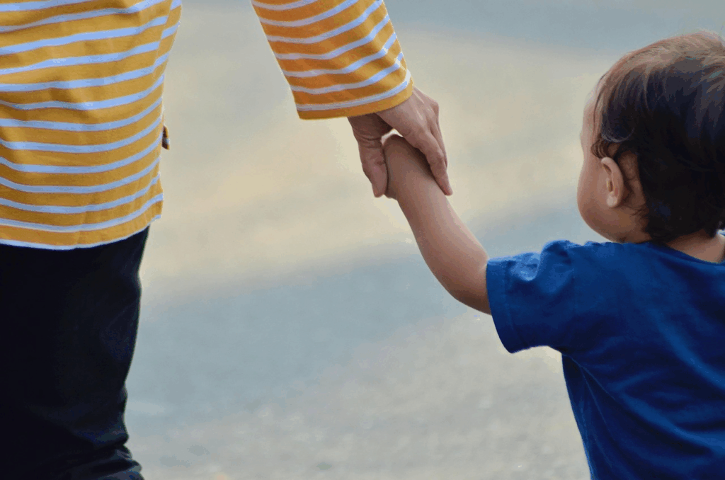 a kid holding his mother's hand