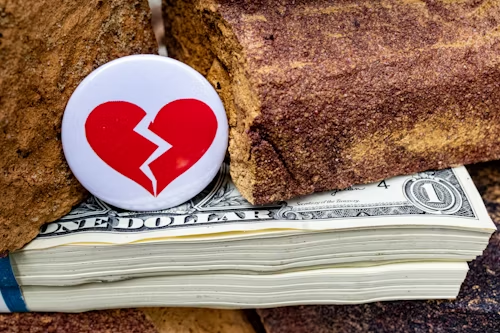 Broken heart placed on a stack of money