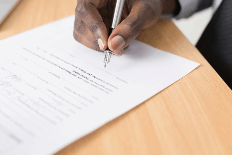 A person signing a legal document on a desk with a pen.