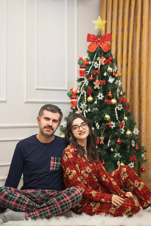 A couple sitting near a Christmas tree