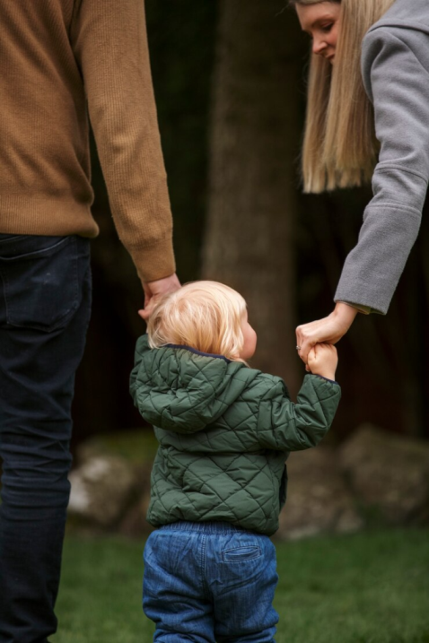 A couple holding their child’s hands
