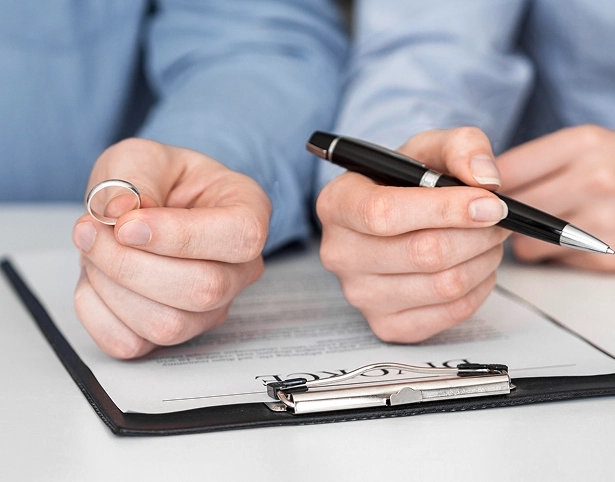 A person is holding a ring while another holds a pen