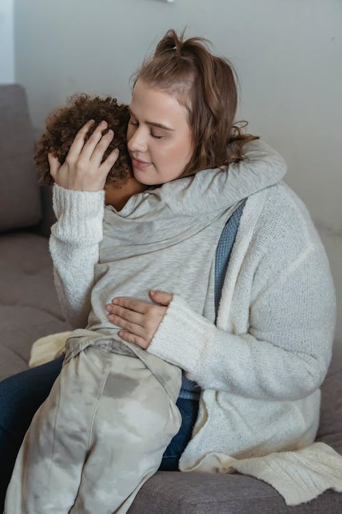 a mother comforting her son sitting on the sofa